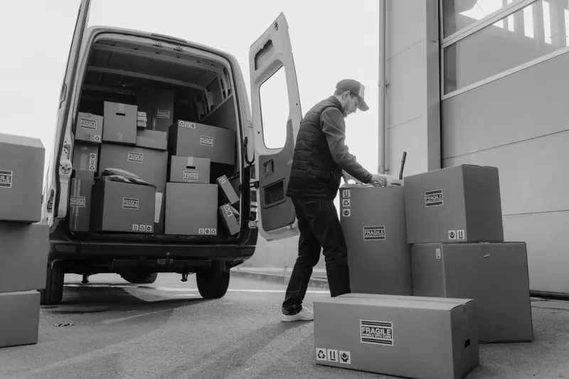 Deux personnes sortent des cartons d’un fourgon.