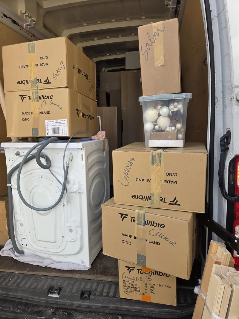 Appareil ménager et cartons dans un véhicule.
